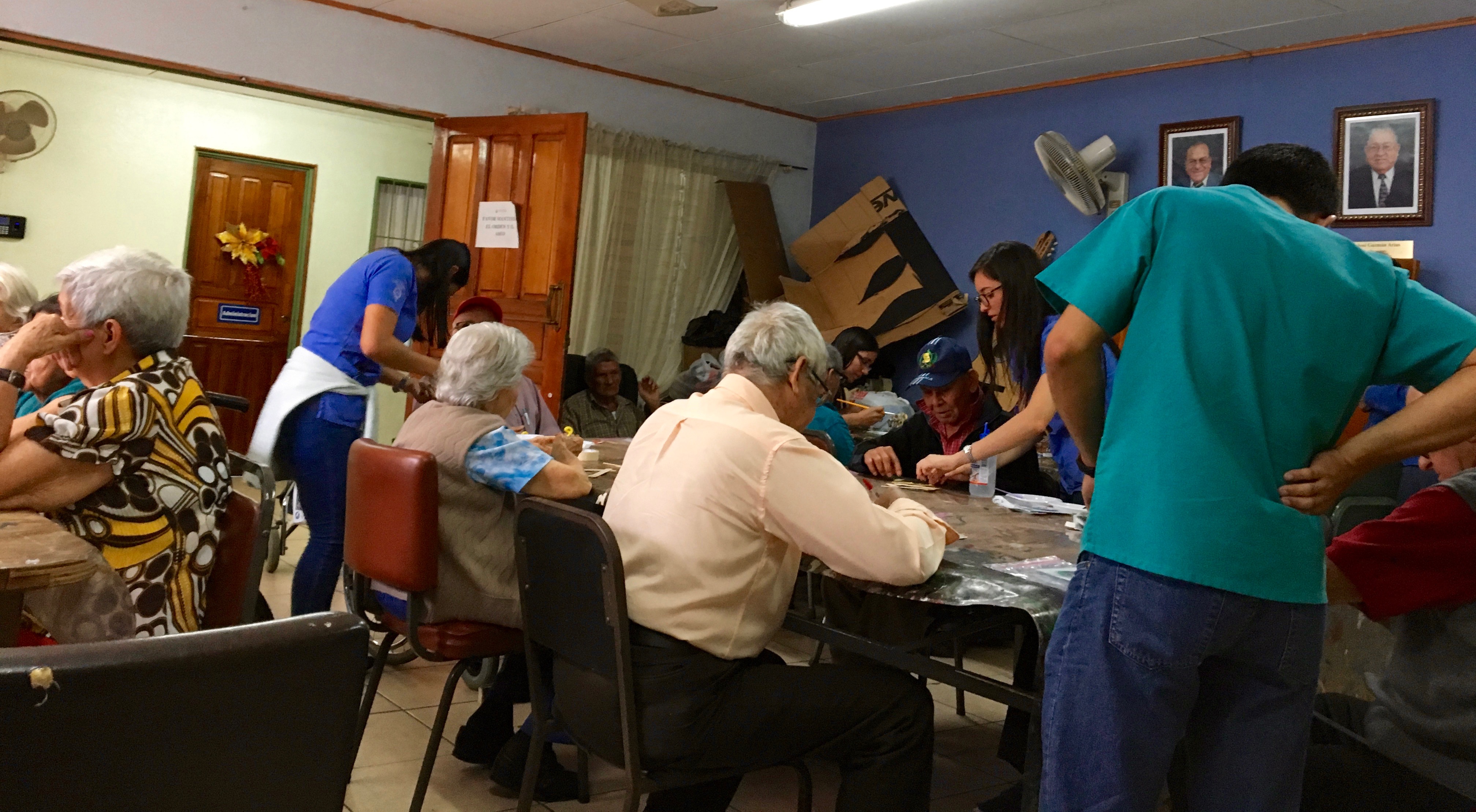 Grupo de personas adultas mayores alrededor de una mesa, participan en un juego.