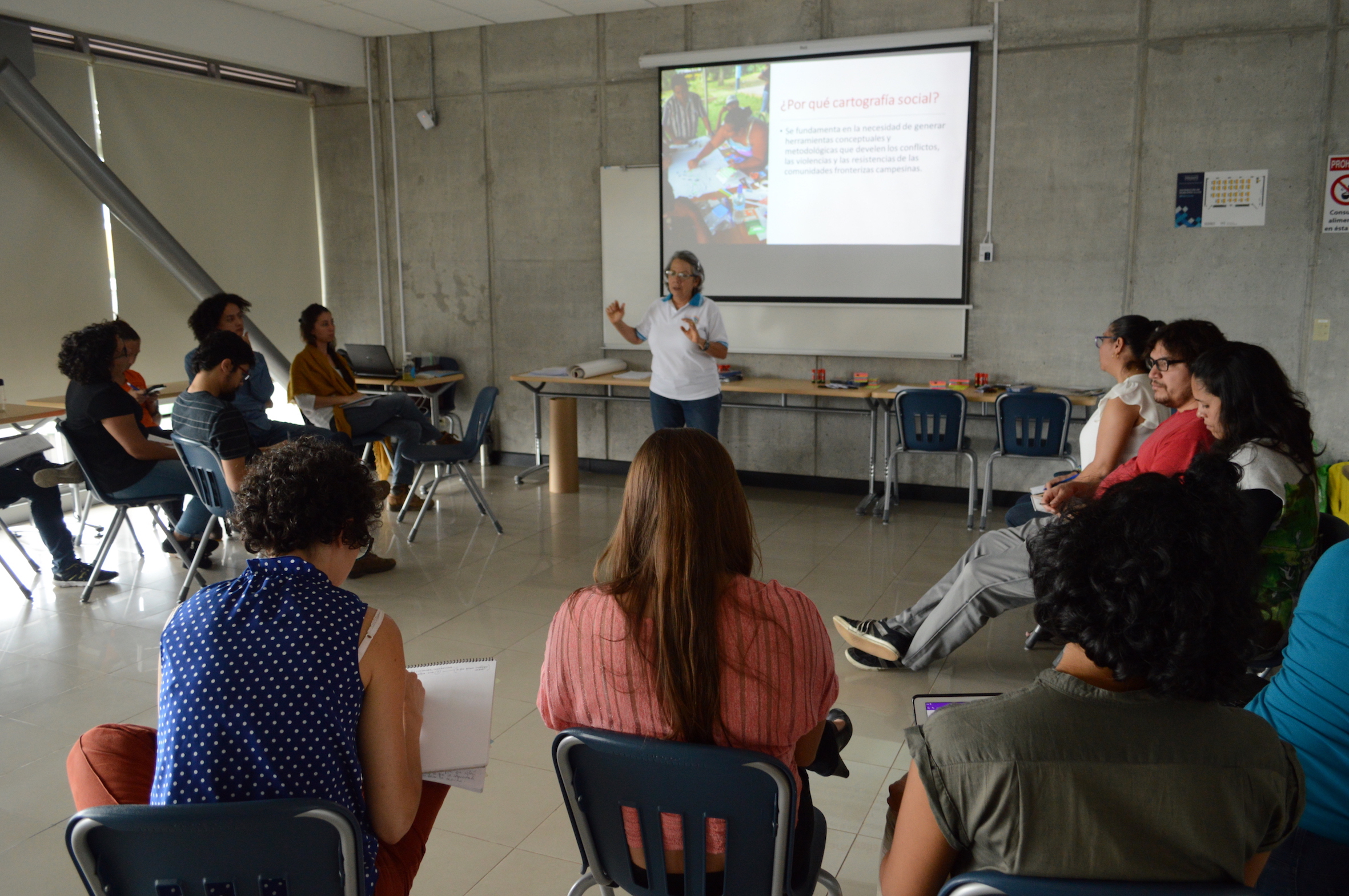 img-noticia-Funcionarios de la Vicerrectoría de Acción Social y estudiantes de la UCR sentados alrededor de Adilia Solís, mientras imparte un taller de cartografía social.