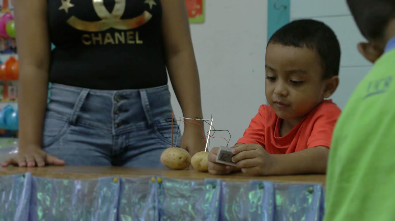 El estudiante Naydel Mercado presenta su experimento científico a sus compañeros de clase en compañía de su mamá. Foto por: Mónica Ureña. 