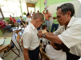 El director de la Escuela San Rafael coloca la insignia de guardián de la Estación al estudiante Luis David Pérez Cambronero.